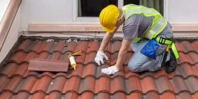 Roofer repairing terracotta roof tiles on a London residential property